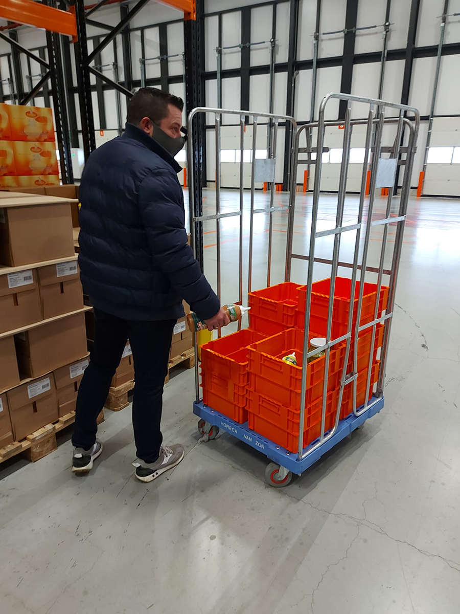 Man vult draaistapelbakken met producten in het magazijn